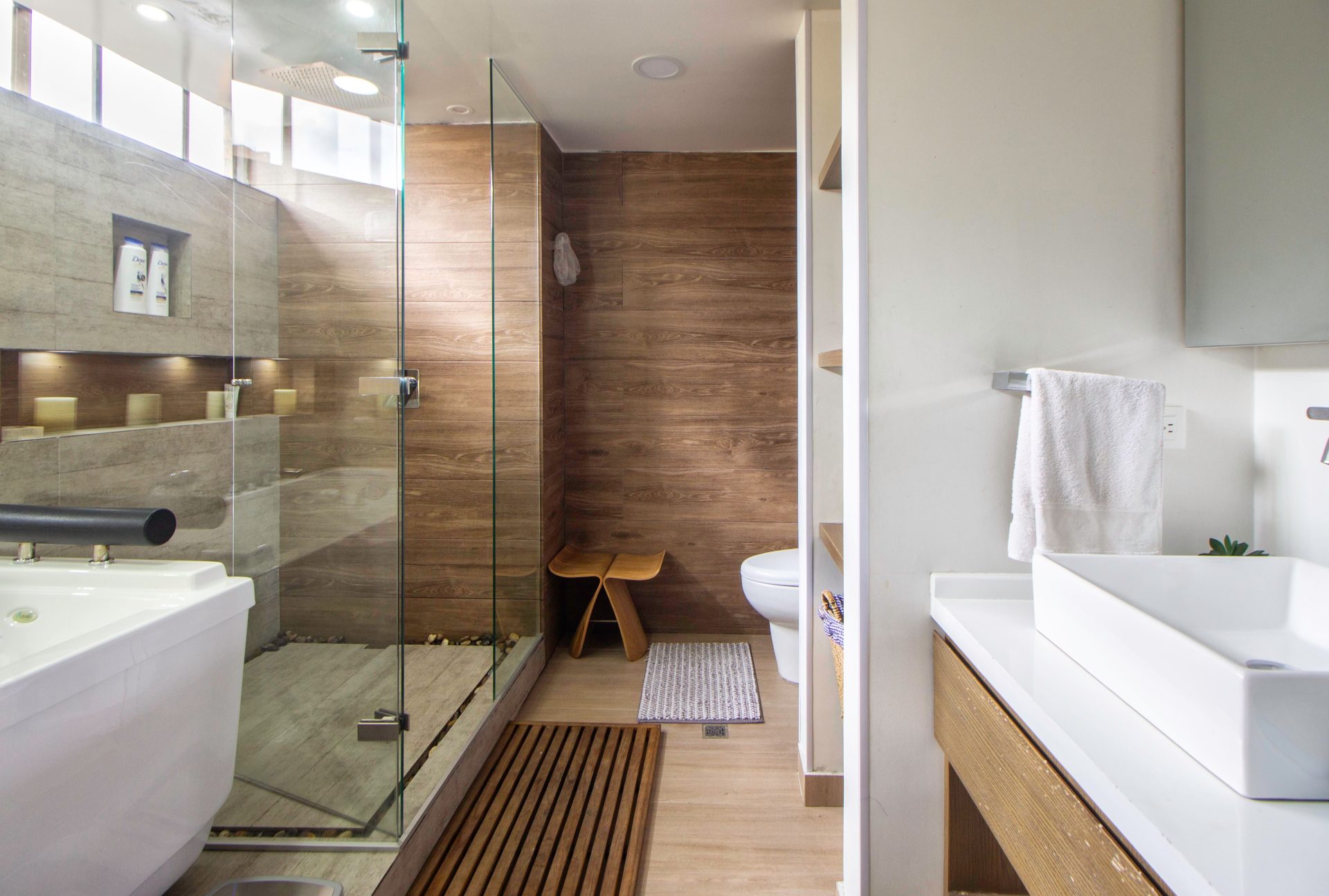 Elegant and modern bathroom featuring a glass shower, wooden accents, and a sleek sink design.
