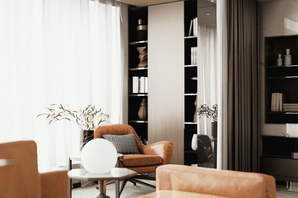 Elegant interior with an armchair, round lamp, and filled bookshelves.